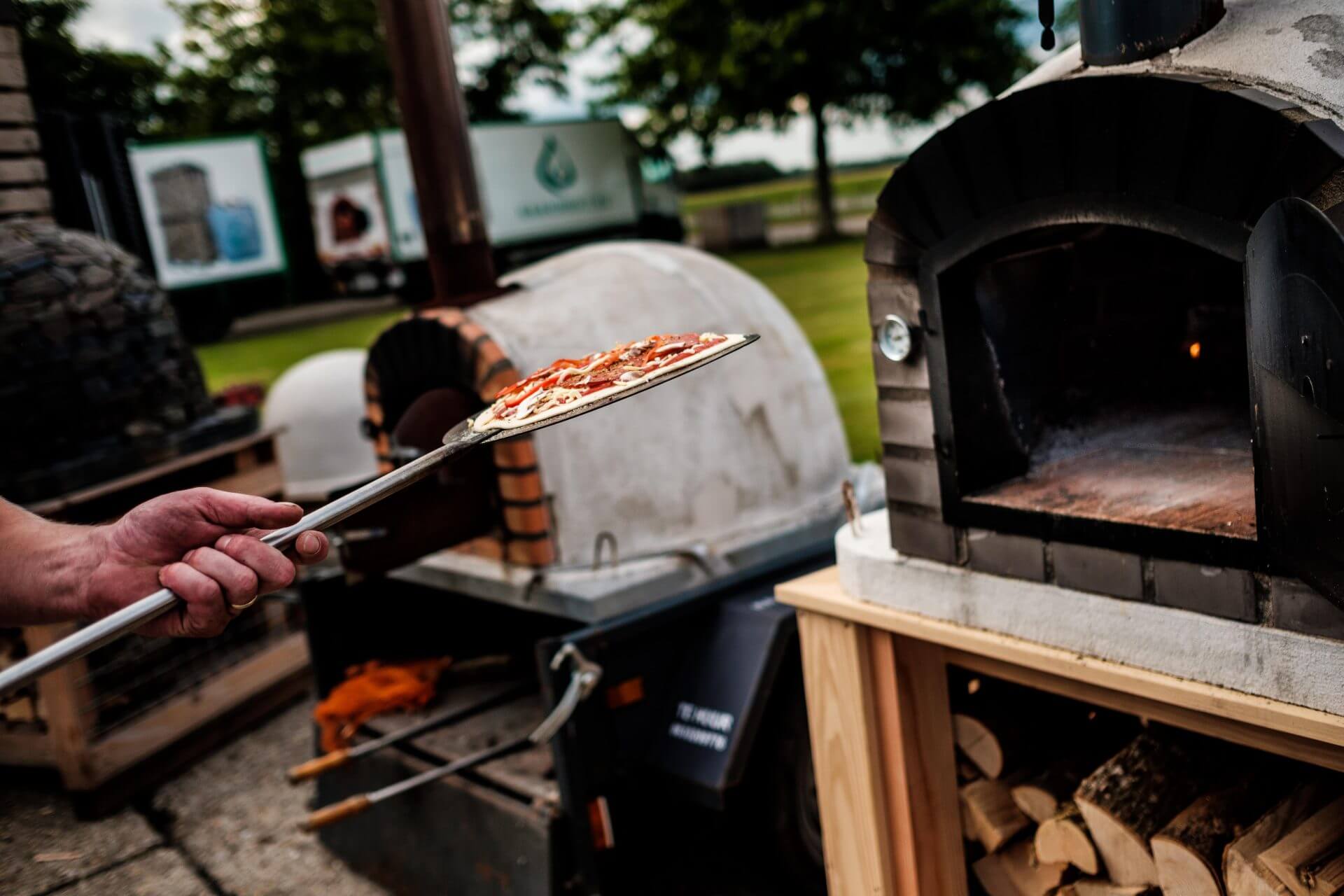 pizza's bakken met pizza schep in houtoven